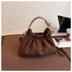 Détails du sac nuage en daim marron foncé montrant la texture plissée et les boucles argentées