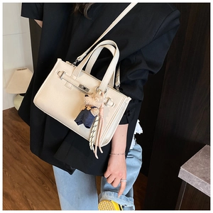 Detail of cream leather square bag with litchi texture and cute bear charm pendant