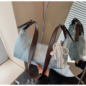 Detail der hellblauen Denim-Hobo-Tasche mit Strass-Glitzer und Perlen-Schleifen-Anhänger