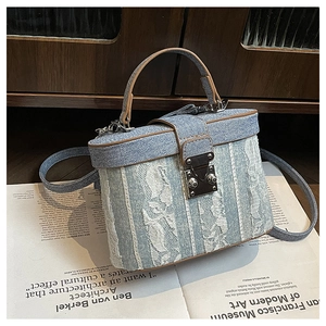 Detailed macro of denim and lace patchwork box bag with brown leather trim and lock