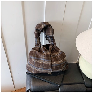 Detail of checkered tote bag featuring a creative knotted handle and vintage fabric texture