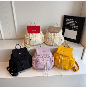 Detailed multi-color display of nylon travel backpacks featuring drawstring and flap closure