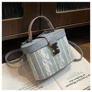 Close-up of denim bucket bag with white floral lace overlays and metal push-lock