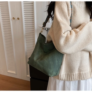 Detail of dark green suede hobo bag featuring ethnic embroidered wide shoulder strap