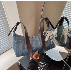 Detail der blauen Denim-Hobo-Tasche mit Strasssteinen und weißem Spitzenbogen-Anhänger