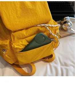 Detail view of a yellow nylon backpack side zipper pocket holding a smartphone