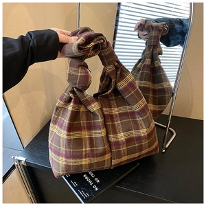 Close-up of a purple and yellow plaid knit tote bag with a unique knot handle design