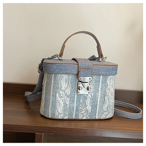 Detail view of denim and lace bucket bag with leather trim and silver metal clasp