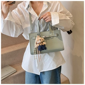 Detail of light green faux leather mini bag with silver buckle and cute bear charm