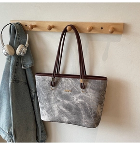 Detail of grey marble textured tote bag with brown leather handles on wooden hook