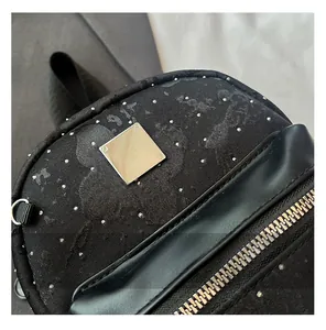 Close-up of black fabric backpack featuring silver metal studs and a square plaque