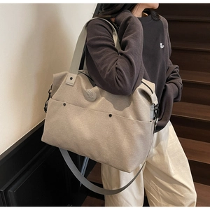 Large beige canvas fitness bag with round leather logo and detachable strap shown on stairs