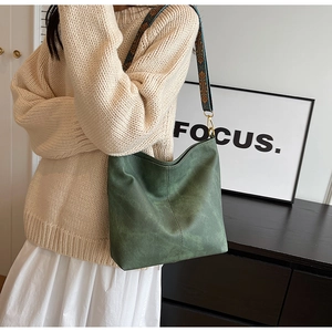 Detail of green suede tote bag with ethnic print shoulder strap shown in a lifestyle setting