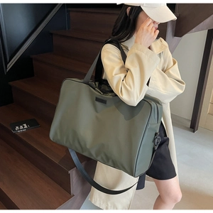 Detail of olive green waterproof nylon travel bag with black straps on a staircase
