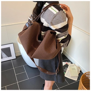 Detail of hobo bag in brown houndstooth fabric with adjustable wide leather strap