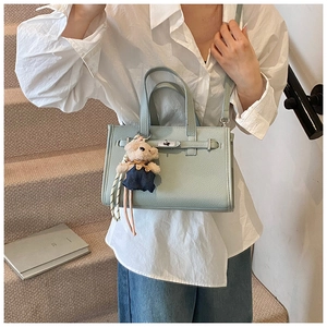 Detail of mint green lychee pattern leather bag with silver lock and bear charm
