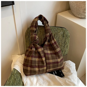 Detail of vintage plaid texture fabric and knot handle design on this tote handbag