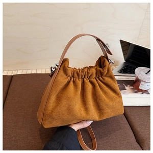 Sac nuage en daim marron plissé sur un bureau avec ordinateur et tasse de café