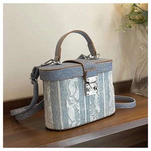 Detailed shot of box-style handbag featuring blue denim and white lace stitching detail