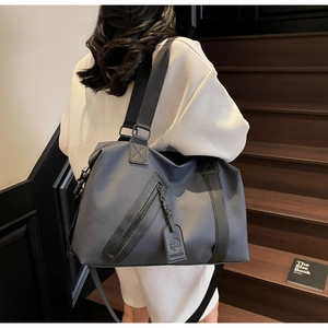Close-up of durable navy nylon travel bag with crossbody strap and front zipper pocket