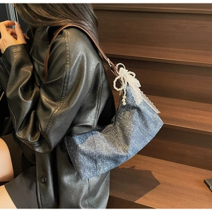 Detail der blauen Denim-Hobo-Tasche mit weißen Punkten und Perlenband-Accessoire
