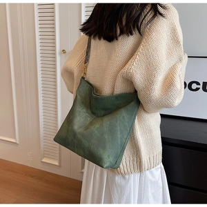Close-up of a forest green suede hobo bag with a patterned ethnic style fabric strap