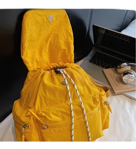 Detailed view of bright yellow nylon backpack with drawstring opening and magnetic flap closure