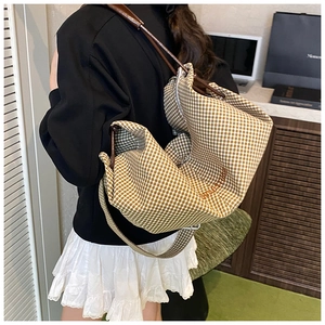 Detail of checkered canvas hobo bag featuring URSTUDIO embroidery and leather shoulder strap