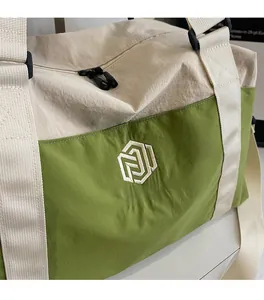 Close-up of durable cream and green nylon fabric with embroidered logo on a travel bag