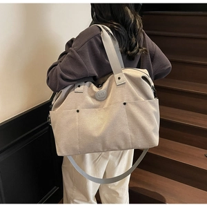 Detail view of canvas travel bag with multiple front pockets and adjustable shoulder strap