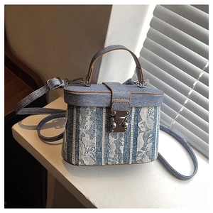 Detail of a denim and floral lace box bucket bag with metal clasp and top handle