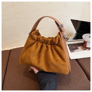 Détail du sac nuage en daim avec poignée en cuir et boucle argentée sur bois rustique
