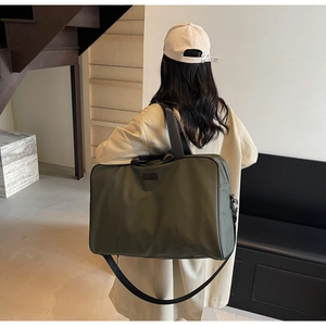 Detail of high-capacity olive green nylon travel bag with black straps and adjustable shoulder belt