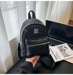 Detailed view of black mini backpack featuring silver polka dots and metal zipper hardware