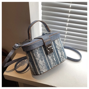 Detail of blue denim box bag with white floral lace and vintage silver metal clasp