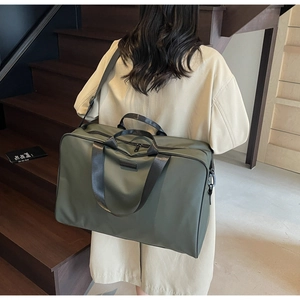 Person carrying an army green nylon travel bag on a staircase for business or leisure