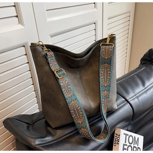 Detail of dark brown suede tote bag featuring a vintage ethnic wide fabric shoulder strap
