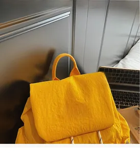 Detail of ginger yellow fashion backpack with woven handle and leather brand patch