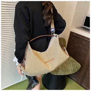 Close-up of checkered tote bag with brown leather straps and mumiastyle embroidery