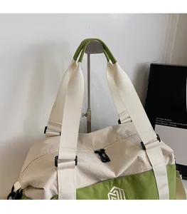 Detail of wide woven shoulder straps and dual zippers on a green travel duffel bag