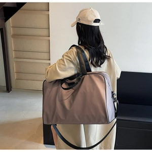 Detail of high-capacity mauve nylon handbag with black straps in a modern indoor setting