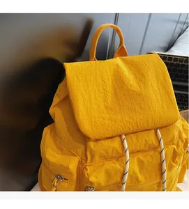 Detail of yellow backpack featuring unique crinkled nylon fabric and woven drawstrings