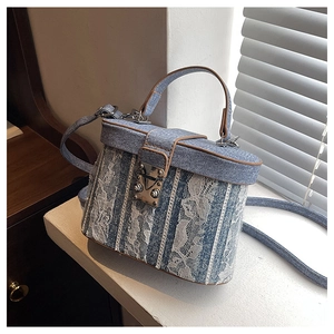 Detail of blue denim bucket bag with white lace trim and vintage silver metal buckle