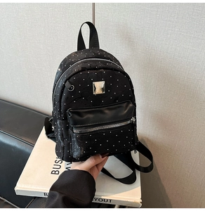 Mini black backpack with white polka dot pattern and front zipper pocket detail