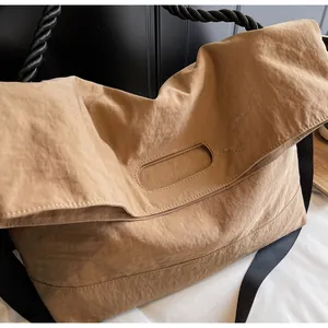 Close-up of khaki nylon tote bag with black woven rope handle and wide crossbody strap