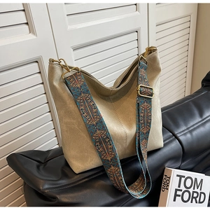 Close-up of beige suede bucket bag with bohemian patterned wide fabric shoulder strap