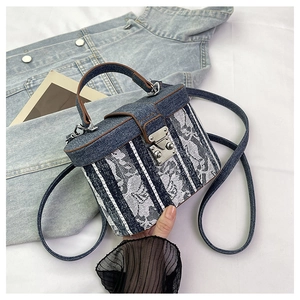 Detail of vintage denim box bag featuring white lace patterns and brown leather straps