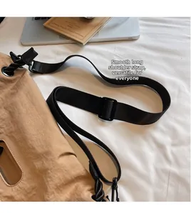 Detail of adjustable black woven shoulder strap with plastic buckle on khaki nylon bag