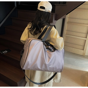 Model wearing a large lavender oxford fabric travel bag on a wooden staircase detail