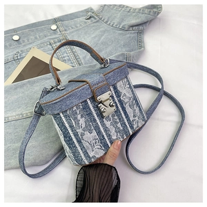 Detail of blue denim and white lace textured bucket bag with silver metal buckle lock